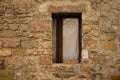 An isolated window with white curtains partially hidden by the stone wall of an abandoned medieval building Gubbio, Umbria