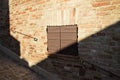 An isolated wooden window with brown shutters in a medieval brick wall Italy, Europe Royalty Free Stock Photo