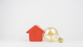 Isolated yellow retro bulb leaning on a red house figurine