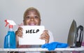 Isolated young attractive and unhappy black afro American woman on kitchen iron board holding notepad with help text written feeli