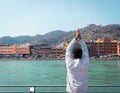 Isolated young man prying the holy ganges river at river bank from flat angle