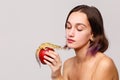 Isolation. Brunette girl holding in her hand a apple on which sits an iguana . The girl is looking at the lizard.