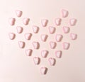 Isometric heart shaped pattern created of heart marshmallows in pink and white color. From above on pastel beige background Royalty Free Stock Photo