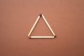 Isosceles triangle on a bright background. matchstick pyramid on cardboard. Education concept