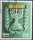 ISRAEL - CIRCA 1990: a postage stamp printed in Israel showing Hanukkah, with Israel`s state emblem, the 7-armed temple candlesti