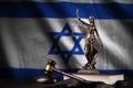 Israel flag with statue of lady justice, constitution and judge hammer on black drapery. Concept of judgement and guilt