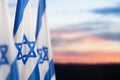 Israel flags with a star of David over cloudy sky background on sunset. Banner with place for text. Royalty Free Stock Photo