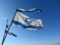 Torn Israeli flags in blue sky with sun beam