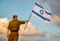 Israeli soldier with Israel flag against a cloudy sky. Remembrance Day - Yom HaZikaron, Patriotic holiday, Israeli Independence