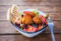 Israeli street food. Falafel salad with hummus, beetroot and vegetables in bowl in a restaurant