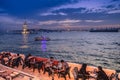 Istanbul Bosporus, a panorama , ships and Maiden`s Tower after sunset. People sit in a cafe on the waterfront. Turkey