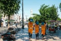 Istanbul, June 15, 2017: Three street janitors in bright orange uniforms are walking down the street holding brooms and