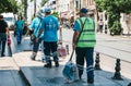 Istanbul, June 15, 2017: Three street janitors in uniforms are walking down the street holding brooms and dust pans.