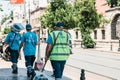 Istanbul, June 15, 2017: Three street janitors in uniforms are walking down the street holding brooms and dust pans.