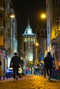 Istanbul nights. People walking on the street and Galata Tower on the background