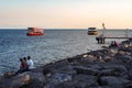 ISTANBUL, TURKEY - AUGUST 21, 2018: people relax on stones on sea shore, boats