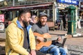 Istanbul, Turkey - December 29, 2022: Two men, one playing guitar and singing, the other listening intently on a city street Royalty Free Stock Photo