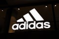 Adidas store neon signboard. Close-up of Adidas logo on dark background
