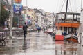 Istanbul Turkey January 31 2019: A man walking down the docks on rainy day. Orange transportation boat is moored on the docks.