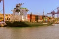 An international freight ship fully loaded with colorful containers, waiting in port.