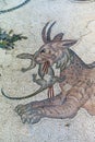 Scene with fantastic animal carrying a lizard in its mouth made with mosaic stones