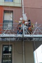 ISTANBUL / TURKEY - JUNE 17, 2019: Two plasterers painters restoring the facade of the house staying in the building cradle Royalty Free Stock Photo