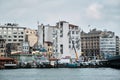 Karakoy shore of istanbul and many pedestrian ferry anchored in golden horn with small fishing boat during overcast and rainy day