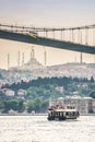 Istanbul, Turkey - May 26, 2017. Bosphorus with boat sailing under the bridge with mosque in background Royalty Free Stock Photo