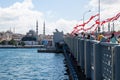 ISTANBUL / TURKEY - 07.17.2020: People fishing on the Golden Horn Halic Bridge, The Yeni Mosque and the Beyazit Tower in the