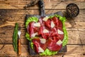 Italian Antipasti Bresaola meat cut with green salad and Parmesan. wooden background. Top view Royalty Free Stock Photo