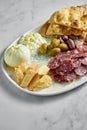 Italian antipasti snacks on white plate on marble background. Focaccia, burrata, olives, sun-dried tomatoes, salami, cheese,