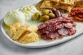 Italian antipasti snacks on white plate on marble background. Focaccia, burrata, olives, sun-dried tomatoes, salami, cheese, Royalty Free Stock Photo