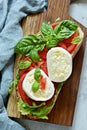 Italian Appetizer Bruschetta toast with Caprese Salad on a wooden board on a blue background