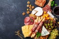 Italian appetizers or antipasto set with gourmet food on black kitchen table top view. Mixed delicatessen of cheese and meat snack Royalty Free Stock Photo