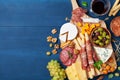 Italian appetizers or antipasto set with gourmet food on blue kitchen table top view. Mixed delicatessen of cheese and meat snacks Royalty Free Stock Photo