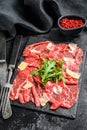 Italian Beef carpaccio with arugula salad, parmesan cheese. Black background. Top view