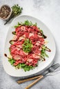 Italian Beef carpaccio with arugula salad, parmesan cheese. Gray background. Top view