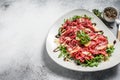 Italian Beef carpaccio with arugula salad, parmesan cheese. Gray background. Top view. Copy space