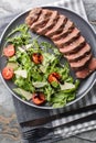 Italian Beef Tagliata salad with wild rocket, cherry tomatoes and parmesan cheese close-up on a plate. Vertical top view Royalty Free Stock Photo