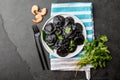 Italian black ravioli with seafood shrimps and crabs on black plate, gray stone slate background. Top view