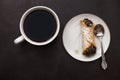 Italian cannoli with chocolate chips on white plate and coffee cup on black background