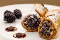Italian cannoli on white plate with blackberries and chocolate chips