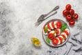 Italian Caprese salad with chopped tomatoes, mozzarella, basil, olive oil on a light stone background. Top view, flat lay, copy Royalty Free Stock Photo