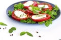 Italian caprese salad with sliced tomatoes, mozzarella cheese, basil, corn salad, olive oil. Served in vintage blue plate on white Royalty Free Stock Photo