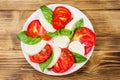 Italian caprese salad with tomatoes, mozzarella cheese and basil on wooden table. Top view Royalty Free Stock Photo