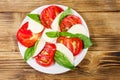 Italian caprese salad with tomatoes, mozzarella cheese and basil on wooden table. Top view Royalty Free Stock Photo