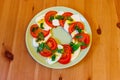 Italian caprese salad with tomatoes, mozzarella cheese and basil on wooden table. Top view Royalty Free Stock Photo