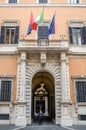 Italian carabiniere policeman guards the entrance at a public institution in a historic building in Rome with the flags of Italy a