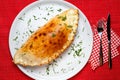 Italian closed pizza Calzone on a large white plate with a knife and fork Royalty Free Stock Photo