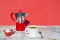 Italian coffee maker, moka pot coffee, cup and saucer of hot drink , sugar on marble table with red background, copy space Royalty Free Stock Photo